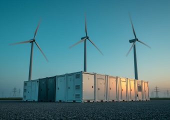Wind turbines and a grid-scale energy storage facility at dusk, representing reliable power delivery from stored wind-generated electricity.