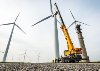 Wind farm with modern wind turbines and service crew and crane near a turbine nacelle during a repowering upgrade.